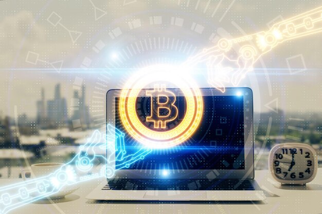 ブロックチェーンと暗号経済テーマのホログラムとコンピューターの背景を持つテーブルの二重露光ビットコイン暗号通貨の概念