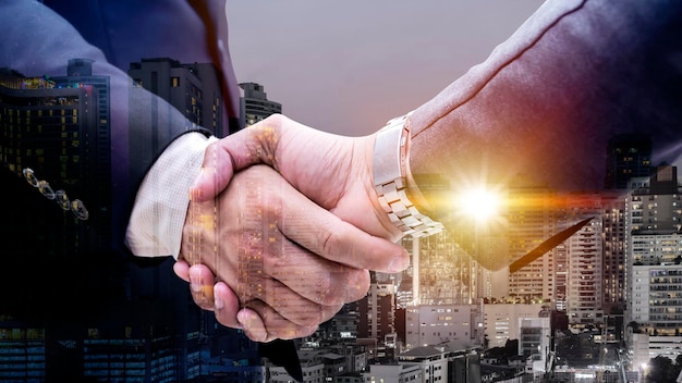 Double exposure of business handshake for successful of investment deal and city night background