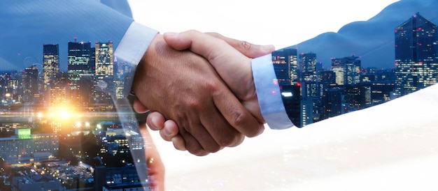 Double exposure businessman investor handshake with partner for successful meeting with night city