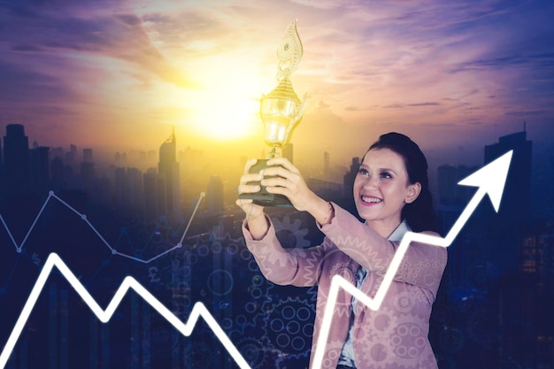 Double exposure of businesswoman holding a trophy