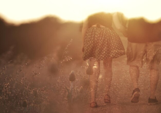 Photo double exposure of couple walking on field against sunset sky