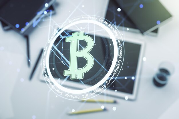 Double exposure of creative Bitcoin symbol hologram and modern digital tablet on background Mining and blockchain concept