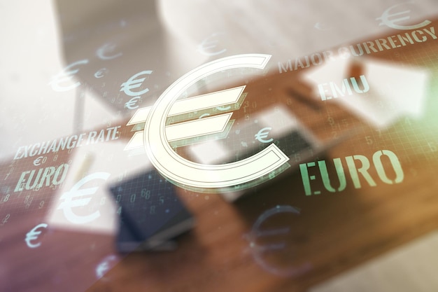 Double exposure of creative EURO symbols hologram and modern desktop with laptop on background Banking and investing concept