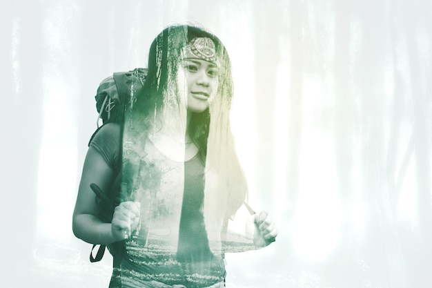 Double exposure of female hiker with misty forest