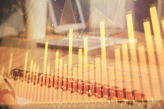 double exposure of financial graph drawings and desk with open notebook background concept of forex market