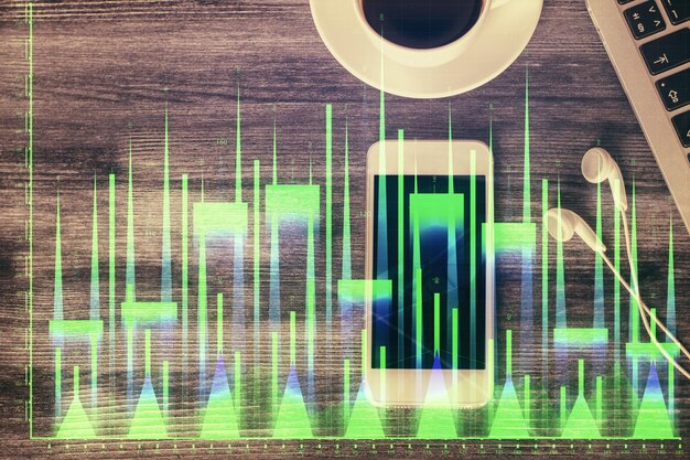 Foto doppia esposizione dell'ologramma del grafico forex sul desktop con il telefono vista dall'alto concetto di piattaforma di commercio mobile