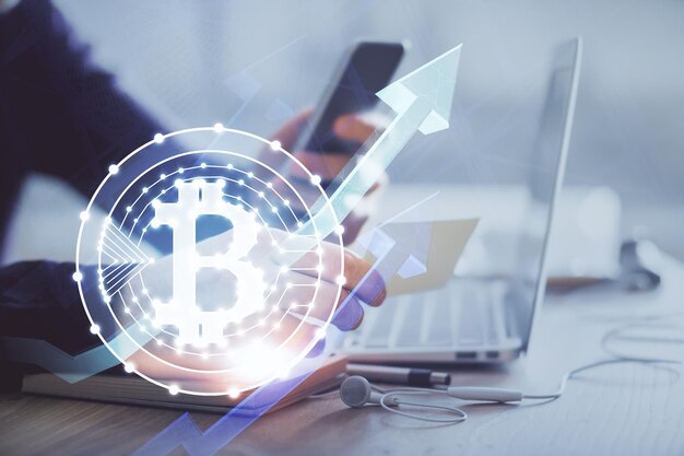 Double exposure of man's hands holding and using a phone and crypto currency blockchain theme drawing