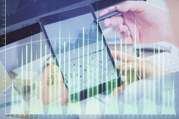 Double exposure of man's hands holding and using a phone and financial chart drawing Market analysis concept