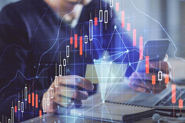 Double exposure of man's hands holding and using a phone and financial graph drawing Analysis concept