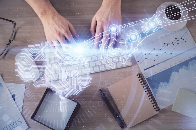 Double exposure of man's hands typing over computer keyboard and brain hologram drawing Top view Ai and data technology concept