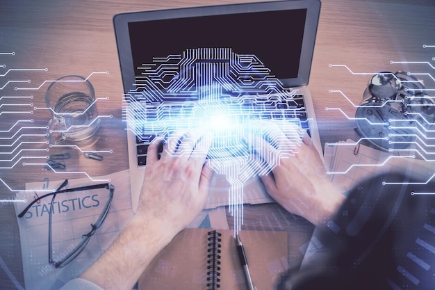 Double exposure of man's hands typing over computer keyboard and brain hologram drawing Top view Ai and data technology concept