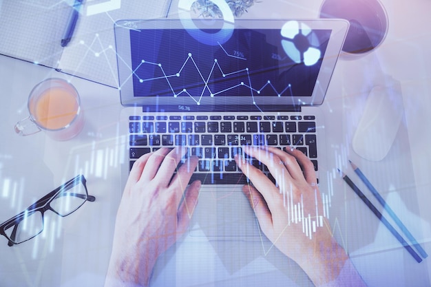 Double exposure of man's hands typing over laptop keyboard and forex chart hologram drawing Top view Financial markets concept