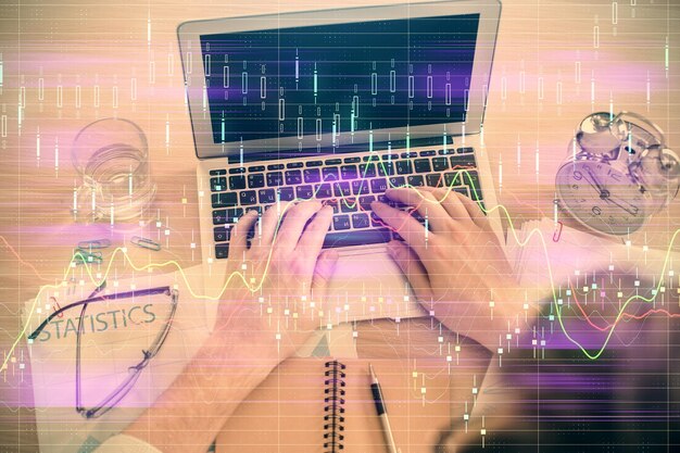 Double exposure of man's hands typing over laptop keyboard and forex chart hologram drawing Top view Financial markets concept