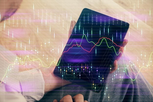 Photo double exposure of mans hands holding and using a digital device and forex graph drawing financial market concept