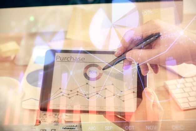 Double exposure of mans hands holding and using a phone and financial chart drawing market analysis concept