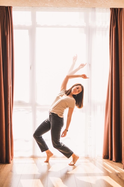 大きな窓の近くで踊る女性の二重露光画像