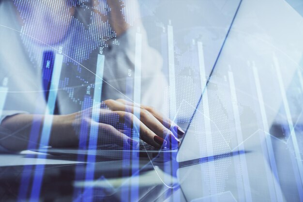 Double exposure of woman hands typing on computer and financial graph hologram drawing Stock market analysis concept