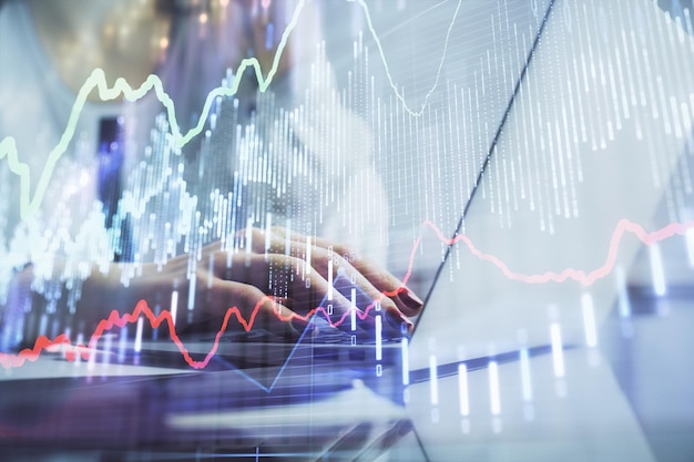 コンピューターに入力する女性の手と財務グラフのホログラム描画の二重露光株式市場分析の概念