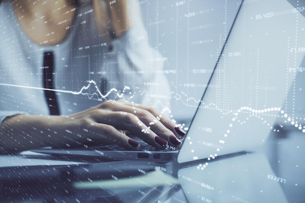 Double exposure of woman hands typing on computer and financial graph hologram drawing Stock market analysis concept