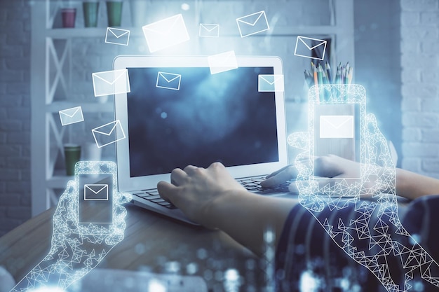 Double exposure of woman hands typing on computer and flying envelop drawing EMail concept