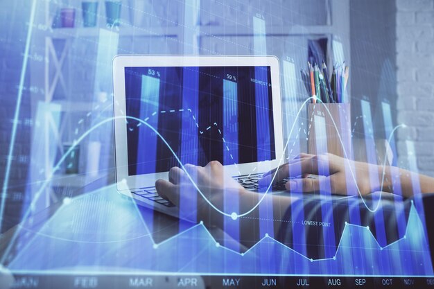 Double exposure of woman hands typing on computer and forex chart hologram drawing Stock market invest concept