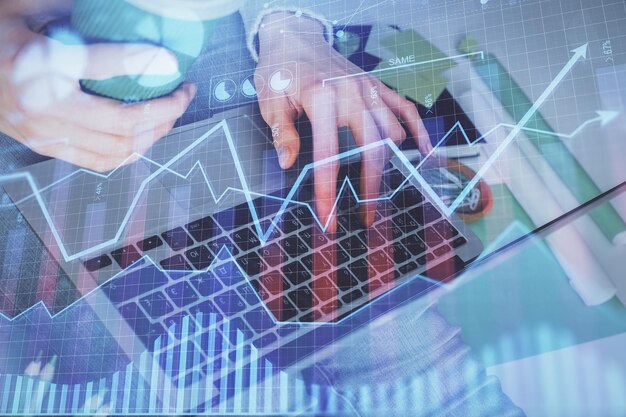 Double exposure of woman hands typing on computer and forex chart hologram drawing Stock market invest concept
