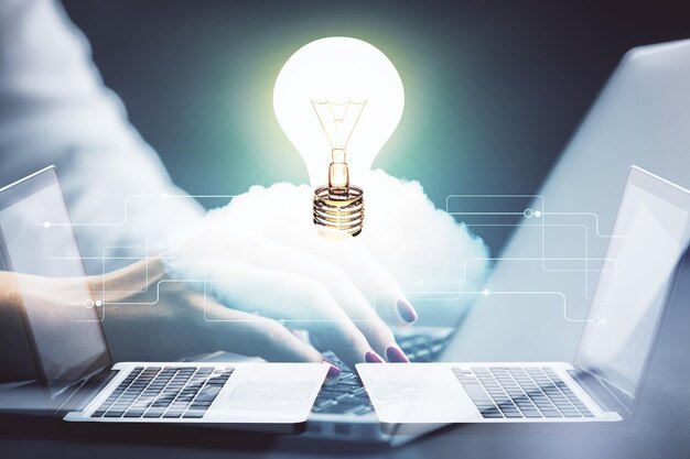 コンピューターに入力する女性の手と電球を描くアイデアコンセプトの二重露光