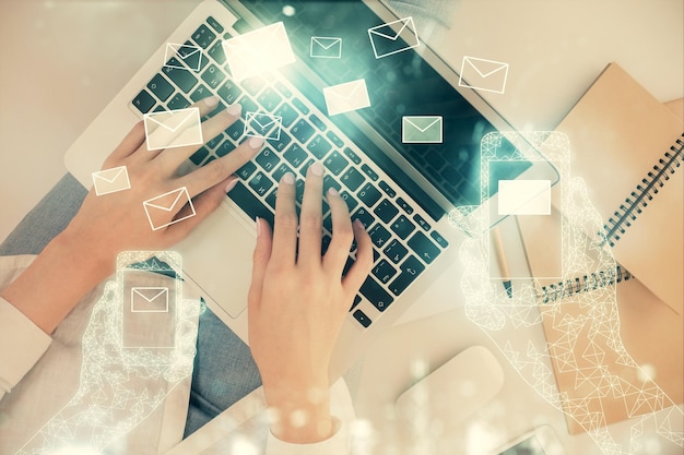 double exposure of woman hands working on computer and envelop hologram drawing top view email concept