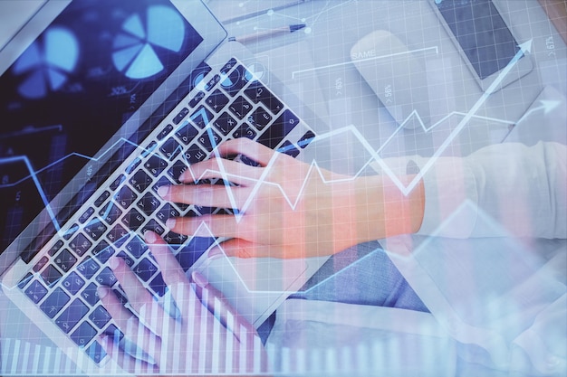 Double exposure of woman hands working on computer and forex chart hologram drawing Top View Financial analysis concept
