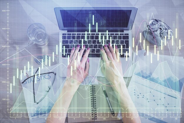 Double exposure of woman hands working on computer and forex graph hologram drawing Top View Financial analysis concept