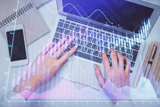 Double exposure of woman hands working on computer and forex graph hologram drawing Top View Financial analysis concept