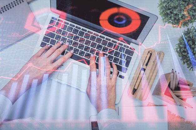 Double exposure of woman hands working on computer and forex graph hologram drawing Top View Financial analysis concept