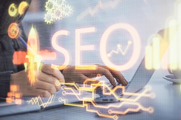 Double exposure of woman hands working on computer and seo hologram drawing internet search concept
