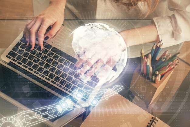 Double exposure of woman hands working on computer and world map hologram drawing International technology business concept