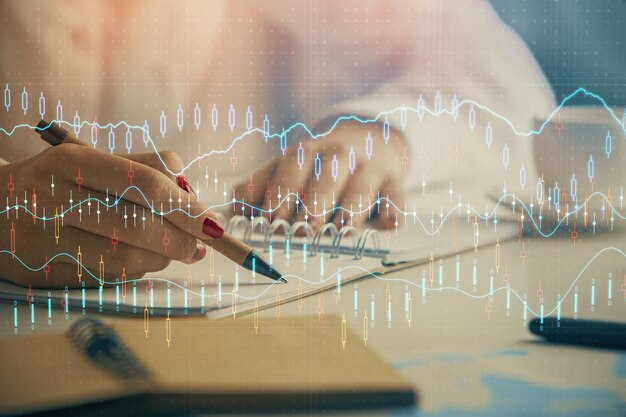 Double exposure of womans hands making notes with forex graph hologram Concept technical analysis