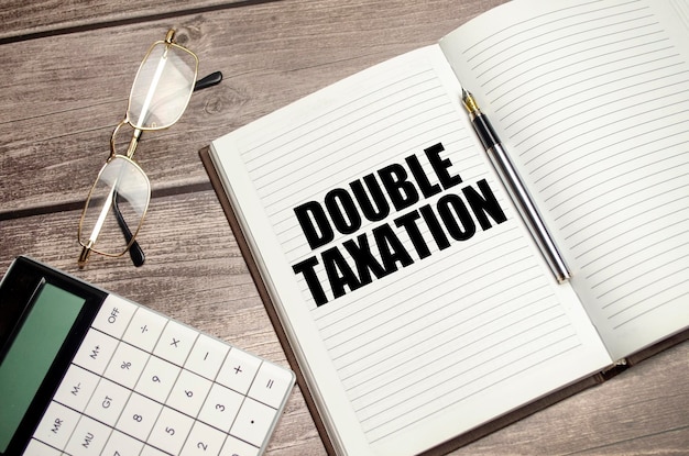 나무 배경 및 계산기에 갈색 일기에 DOUBLE TAXATION 단어