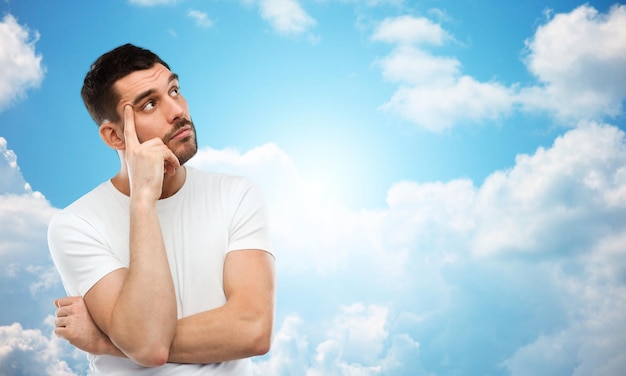 doubt, expression and people concept - man thinking over blue sky and clouds background