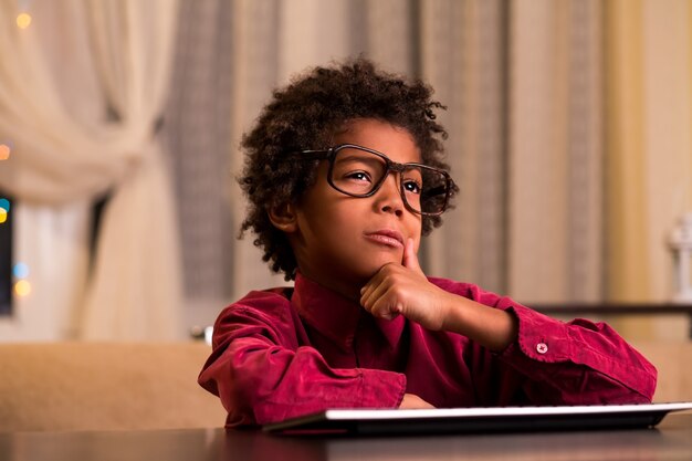 Doubtful black boy at keyboard.