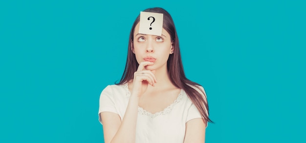 Doubtful girl asking questions to himself. Paper notes with question marks. Confused female thinking with question mark on sticky note on forehead.