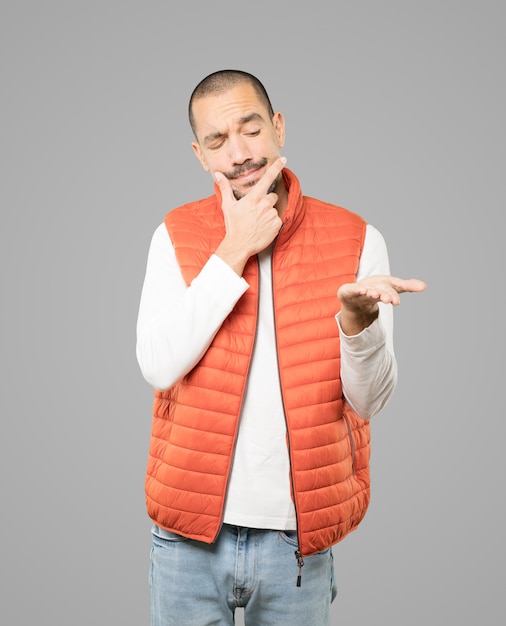 Doubtful young man holding something with his hand