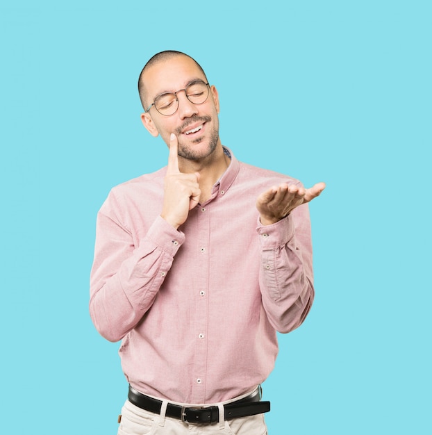 Doubtful young man holding something with his hand