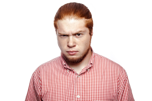 Doubting confused bearded readhead businessman with red shirt and freckles looking at camera