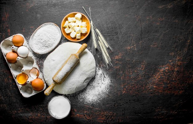 Foto sfondo di pasta impasto con burro, latte e farina in ciotole