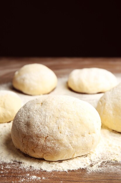 Dough balls for pizza on floured wooden board