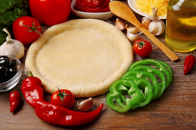 Dough basis and ingredients for pizza on the table