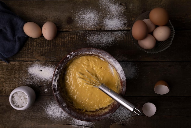 Foto uova di pollo rotte e articoli da cucina su un tavolo di legno