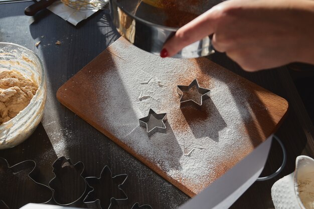 Dough for gingerbread cookies rolled on the wooden board cutting out star shaped cookies