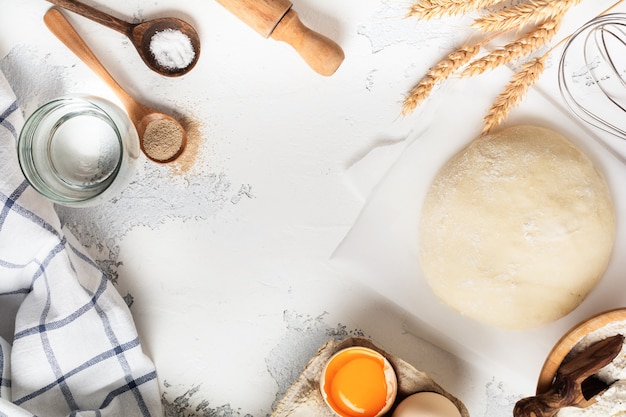 Dough and ingredients for the preparation of pasta, dough, eggs, flour, water and salt on a light rustic old table