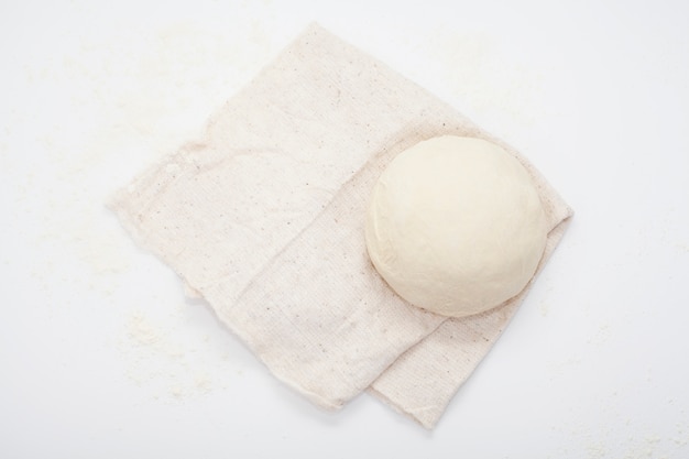 Dough on a kitchen towel, on a white table.