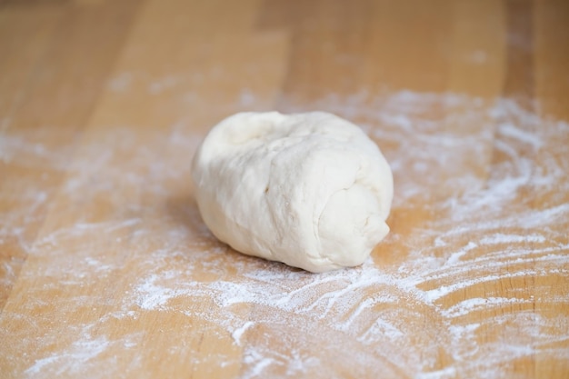 Dough lies in flour on wooden surface closeup